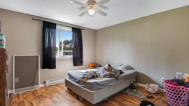 bedroom featuring ceiling fan, baseboard heating, and hardwood / wood-style flooring