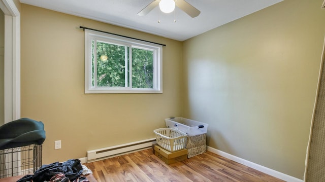 interior space with ceiling fan, a baseboard heating unit, and light hardwood / wood-style flooring