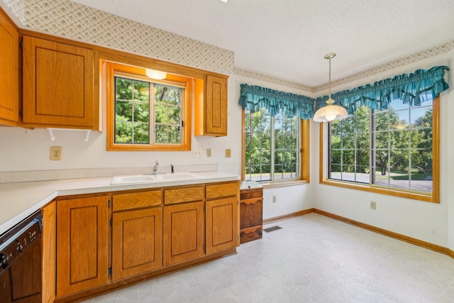 kitchen with a textured ceiling, dishwasher, pendant lighting, and sink