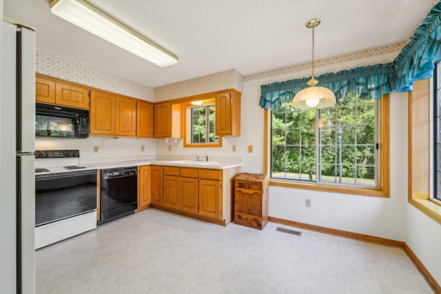 kitchen featuring decorative light fixtures, black appliances, light tile patterned flooring, and sink