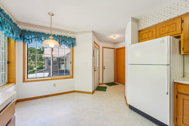 kitchen featuring white fridge, hanging light fixtures, and a textured ceiling