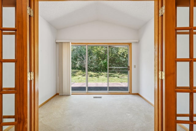 carpeted empty room featuring vaulted ceiling and a textured ceiling