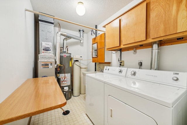 laundry area with gas water heater, heating unit, washer and dryer, cabinets, and a textured ceiling