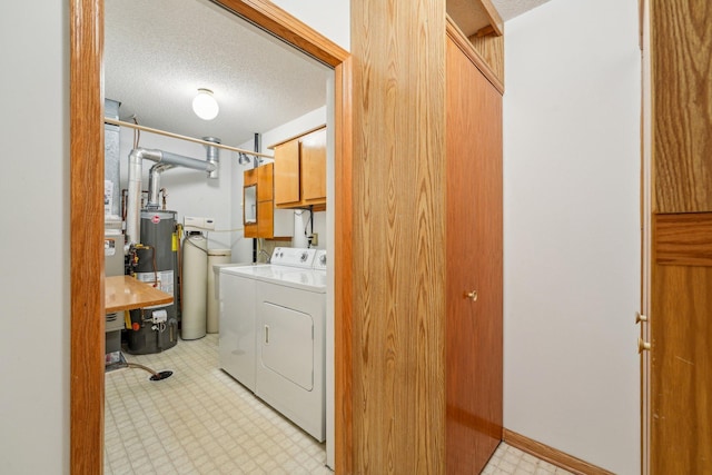 laundry area with gas water heater, cabinets, a textured ceiling, and washer and dryer