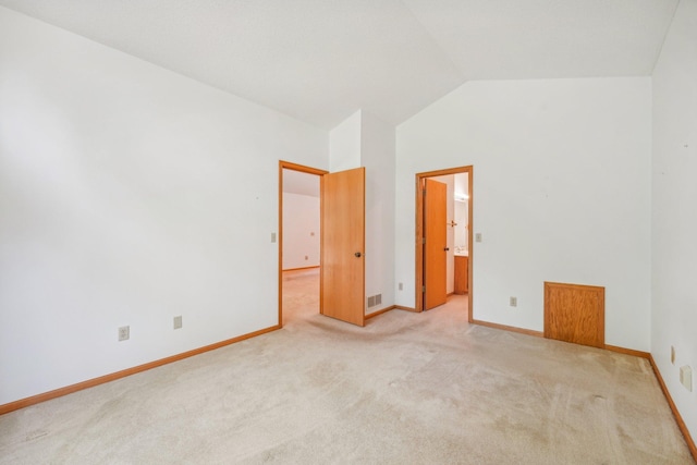 unfurnished bedroom with light colored carpet, vaulted ceiling, and ensuite bathroom