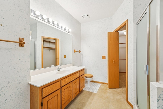 bathroom with vanity, toilet, a shower with shower door, and a textured ceiling