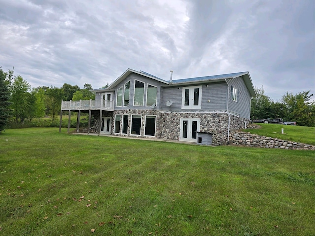 back of house with stone siding, french doors, a yard, and a deck