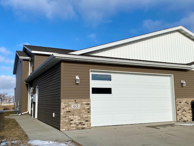 view of property exterior featuring a garage, brick siding, and driveway