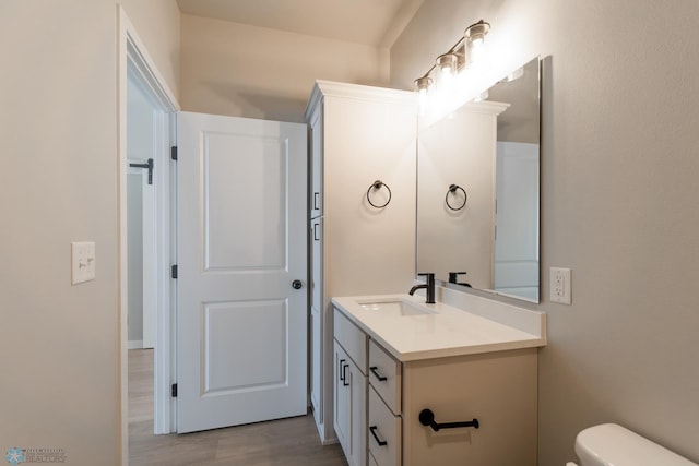 bathroom with vanity, toilet, and wood-type flooring