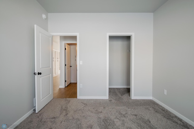 unfurnished bedroom with a walk in closet, a closet, and light colored carpet