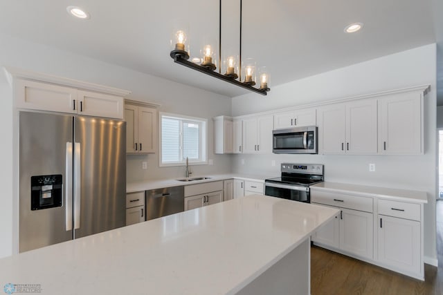 kitchen featuring sink, white cabinets, stainless steel appliances, and decorative light fixtures