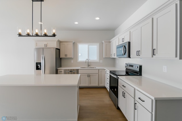 kitchen with white cabinets, hanging light fixtures, sink, appliances with stainless steel finishes, and a notable chandelier