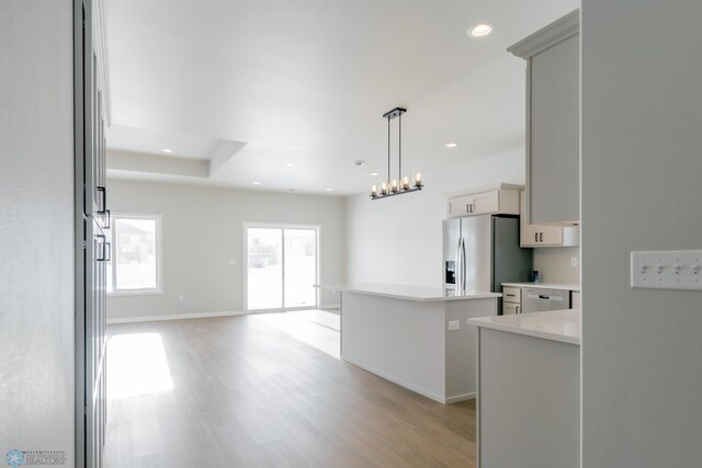 kitchen featuring light hardwood / wood-style floors, a center island, stainless steel fridge with ice dispenser, and hanging light fixtures