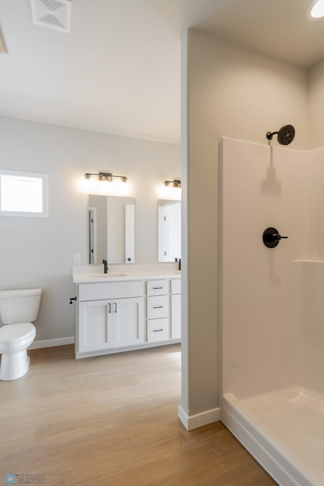 bathroom with vanity, toilet, a shower, and wood-type flooring