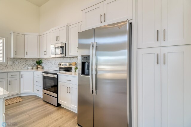 kitchen with white cabinets, stainless steel appliances, light hardwood / wood-style floors, a wealth of natural light, and tasteful backsplash