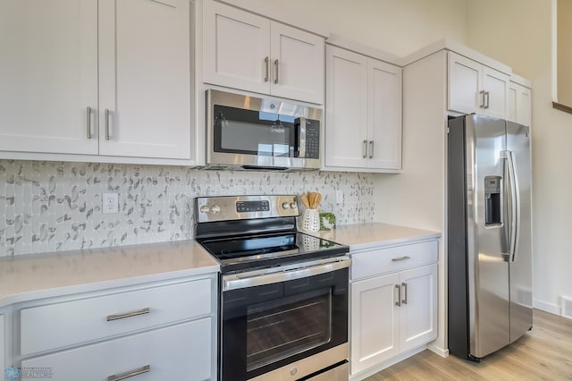 kitchen featuring appliances with stainless steel finishes, tasteful backsplash, light hardwood / wood-style floors, and white cabinetry