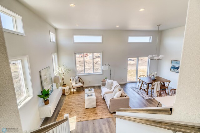 living room featuring plenty of natural light, a towering ceiling, and light wood-type flooring