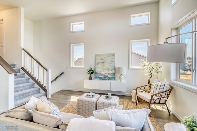 living room featuring light wood-type flooring and a towering ceiling