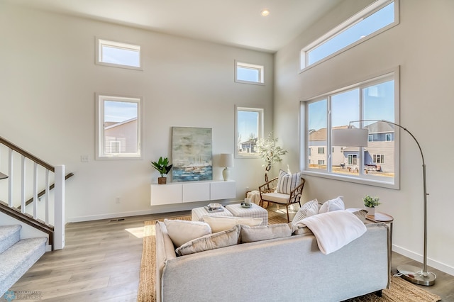 living room with light wood-type flooring, a healthy amount of sunlight, and a high ceiling