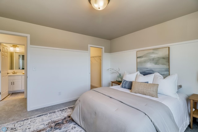 bedroom featuring a walk in closet, ensuite bathroom, light carpet, and a closet