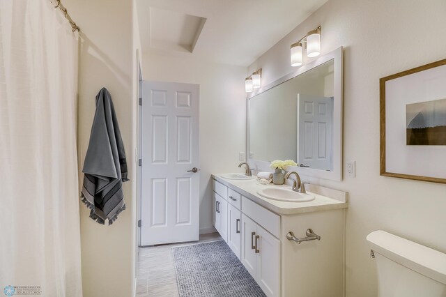 bathroom with tile patterned floors, toilet, and double sink vanity