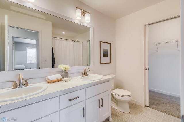 bathroom featuring tile patterned flooring, toilet, and double sink vanity