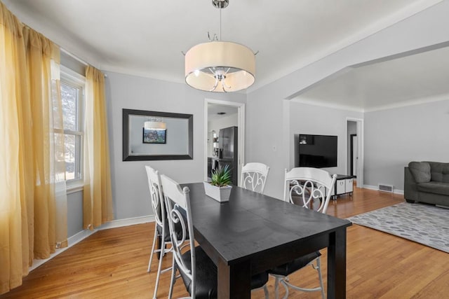 dining space featuring light wood finished floors, baseboards, and visible vents