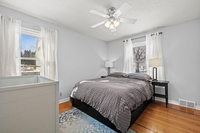 bedroom featuring light wood-style flooring, multiple windows, visible vents, and baseboards