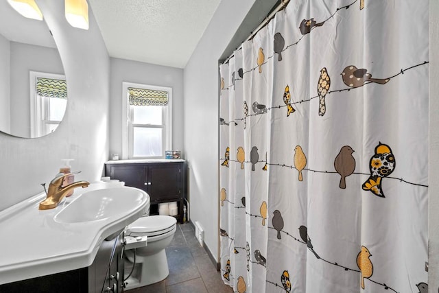 bathroom featuring vanity, a textured ceiling, toilet, and tile patterned floors