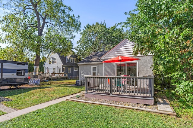 back of house with a lawn, a wooden deck, and central air condition unit