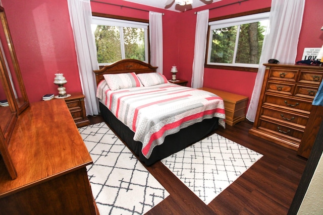 bedroom featuring ceiling fan, multiple windows, and wood finished floors