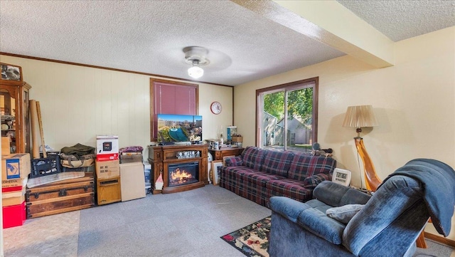 living room featuring a textured ceiling, a lit fireplace, and carpet flooring