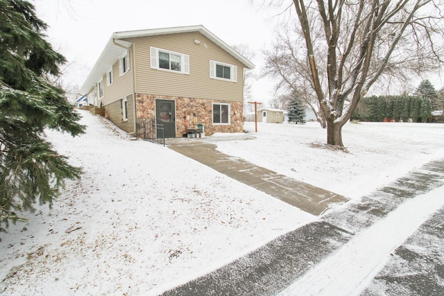 snow covered rear of property with stone siding