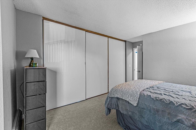 carpeted bedroom with a textured ceiling and a closet