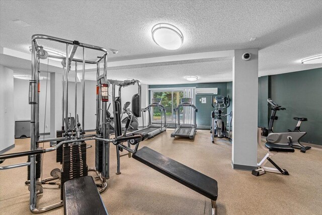 gym featuring a wall mounted AC and a textured ceiling