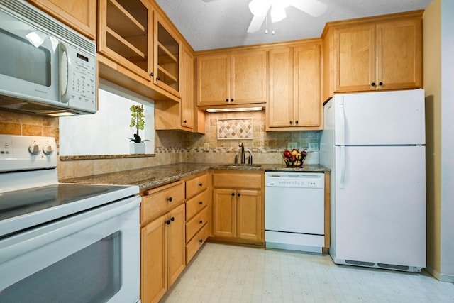 kitchen with dark stone counters, a textured ceiling, sink, white appliances, and ceiling fan