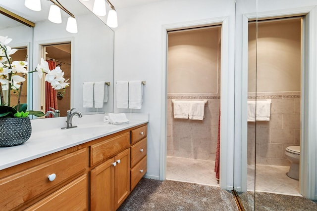 bathroom with tile walls, toilet, tile patterned floors, vanity, and curtained shower