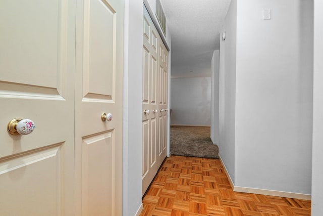 corridor with light parquet floors and a textured ceiling