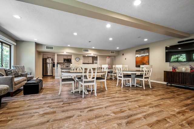 dining area with light wood-type flooring and a textured ceiling