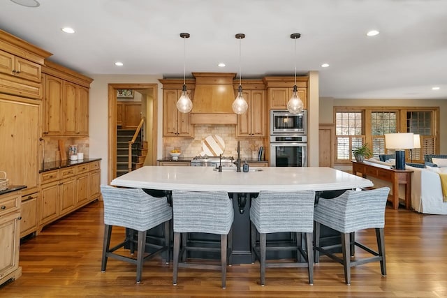 kitchen with appliances with stainless steel finishes, an island with sink, and hanging light fixtures