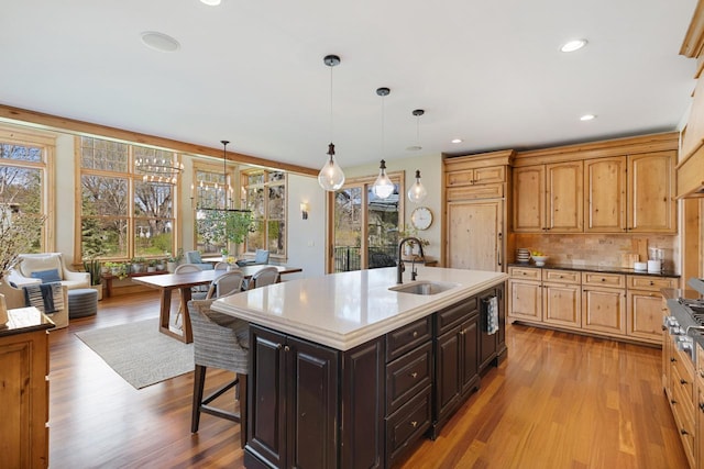 kitchen featuring light hardwood / wood-style floors, sink, a center island with sink, and pendant lighting