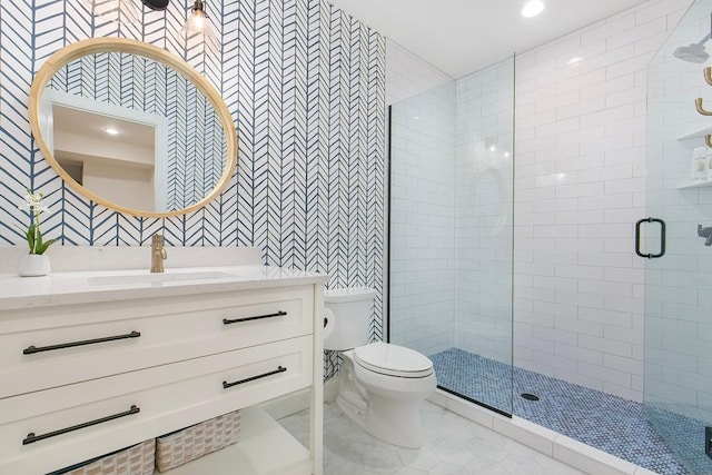 bathroom featuring toilet, a shower with shower door, and vanity