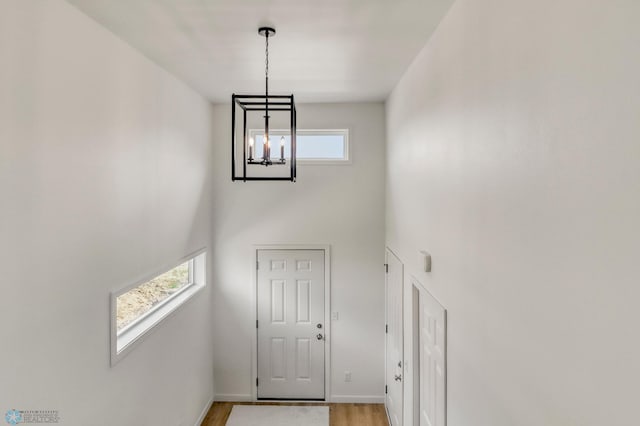 7043 Benji Ln, Fargo, ND 58047 - foyer featuring a chandelier, a towering ceiling, light wood-style floors, and baseboards