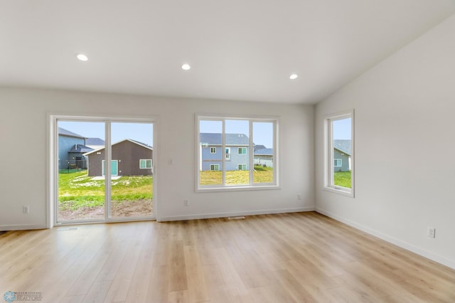 7043 Benji Ln, Fargo, ND 58047 - unfurnished room featuring plenty of natural light, light wood-type flooring, baseboards, recessed lighting, and vaulted ceiling