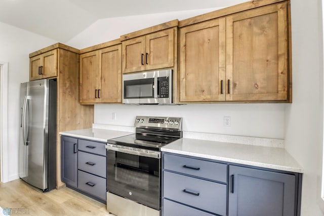 7043 Benji Ln, Fargo, ND 58047 - kitchen featuring stainless steel appliances, light wood-style flooring, light countertops, lofted ceiling, and brown cabinetry