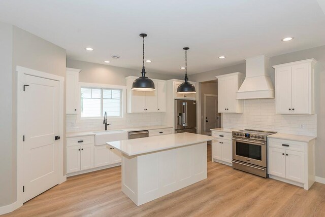 kitchen with sink, light wood-type flooring, white cabinetry, stainless steel appliances, and custom exhaust hood