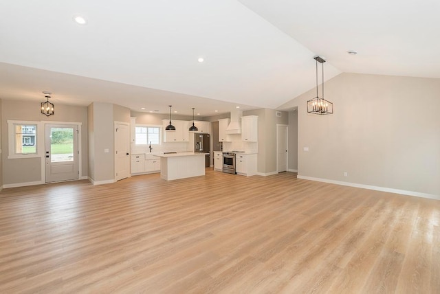 unfurnished living room with vaulted ceiling, a notable chandelier, and light hardwood / wood-style floors