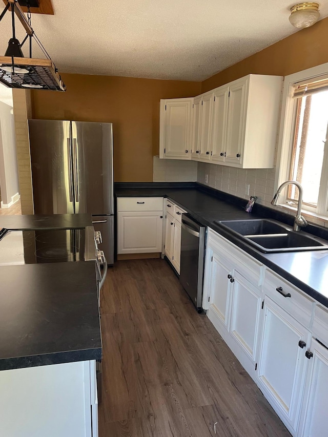 kitchen with appliances with stainless steel finishes, white cabinetry, sink, and dark wood-type flooring