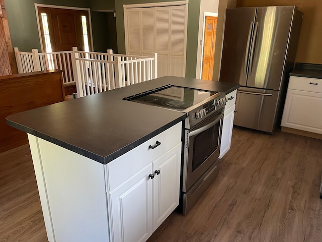 kitchen with white cabinets, stainless steel appliances, a kitchen island, and dark hardwood / wood-style flooring