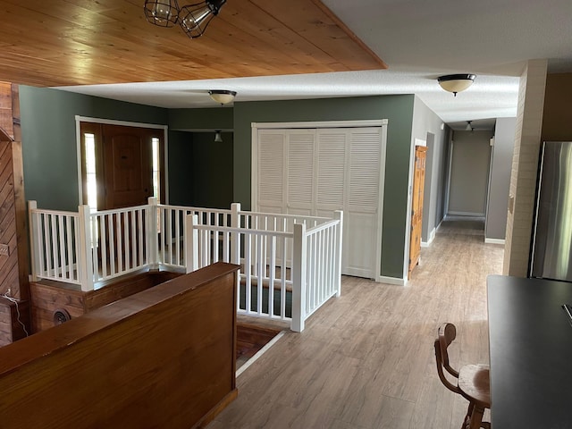 corridor with light hardwood / wood-style flooring and wood ceiling